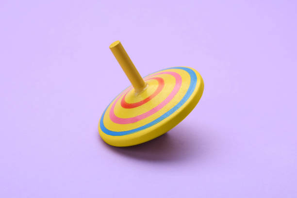 istock One bright spinning top on lilac background. Toy whirligig 1905543041