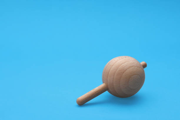istock One wooden spinning top on light blue background, space for text. Toy whirligig 1905545678