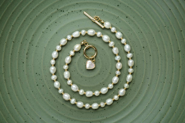 istock Elegant pearl necklace on olive textured background, top view 1905546699