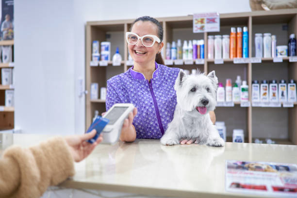 istock Friendly veterinary woman with a client's dog shows the dataphone while the client brings his credit card to pay wirelessly 1905547212