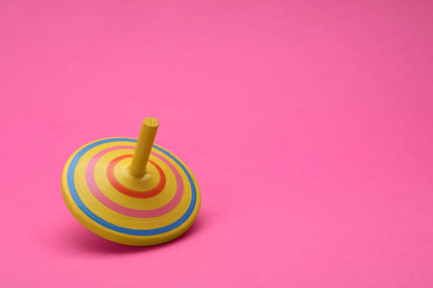 istock One bright spinning top on pink background, space for text. Toy whirligig 1905548763