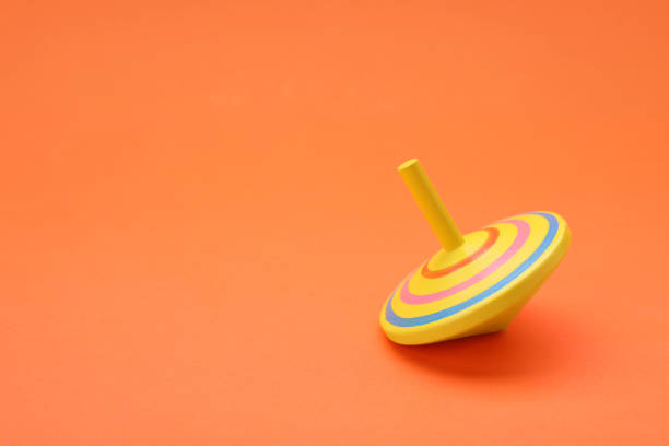 istock One bright spinning top on orange background, space for text. Toy whirligig 1905550294