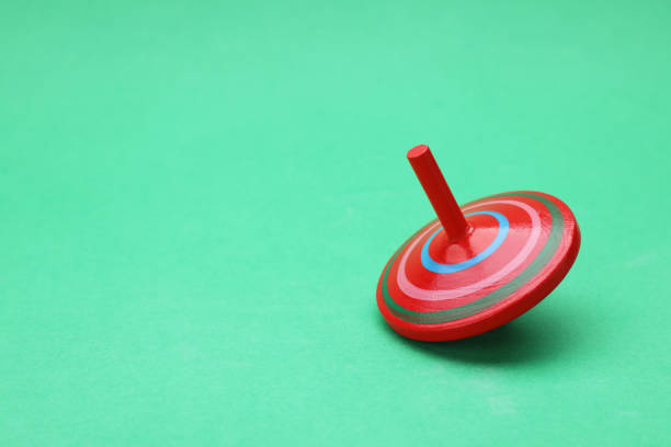 istock One bright spinning top on green background, space for text. Toy whirligig 1905553350