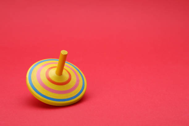 istock One bright spinning top on red background, space for text. Toy whirligig 1905555369