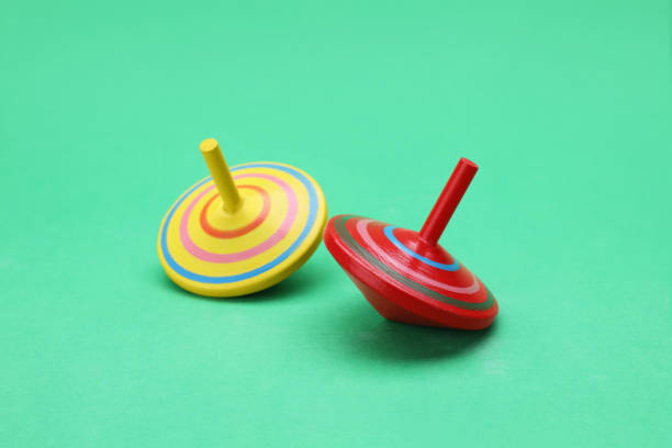 istock Two bright spinning tops on green background. Toy whirligig 1905556383