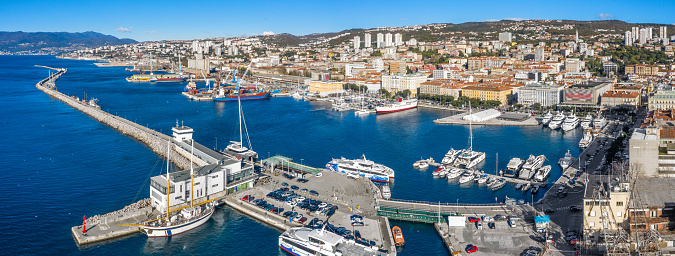 San Diego, California, USA - October 4, 2021: Embarcadero boardwalk. Fishing vessels docked at Tuna Harbor with Midway aircraft carrier museum in back under blue cloudscape.