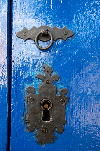 Antique knocker and lock on old blue wooden door, on colonial city of Tiradentes, Minas Gerais state, Brazil