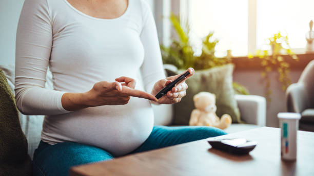 a pregnant woman hands using lancet on finger to check blood sugar test level by glucose meter - diabetes human pregnancy women blood sugar test fotografías e imágenes de stock