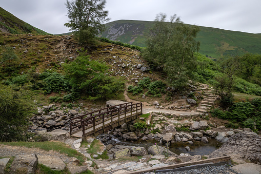 Picturesque footbridge crossing a stream in a lush mountain landscape - Wales Coastal Path at Aber Falls (Rhaeadr Fawr) North Wales
