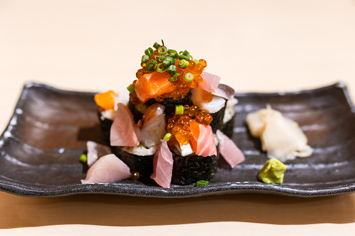 A close-up shot of tuna, fish eggs, and salmon sashimi dish with sushi at a Japanese restaurant.