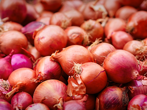 Red onions for sale close-up in street market stall