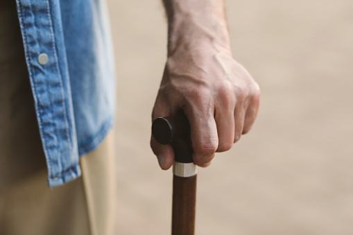 Senior man with walking cane outdoors, closeup