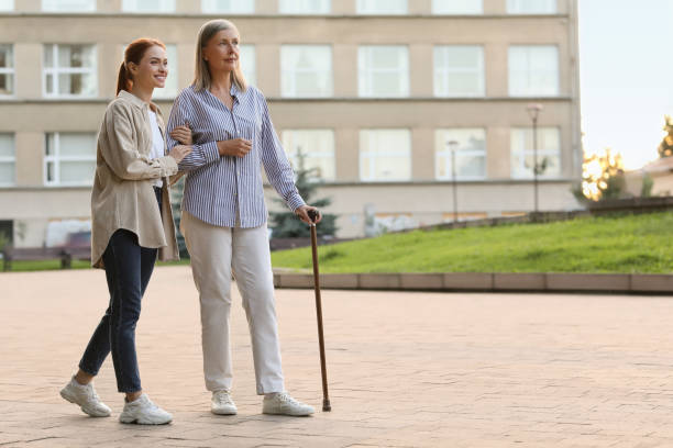 istock Senior lady with walking cane and young woman outdoors. Space for text 1905691256