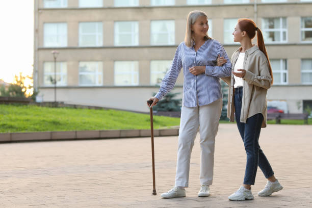 istock Senior lady with walking cane and young woman outdoors. Space for text 1905692807
