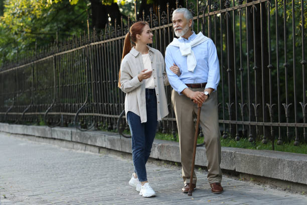 istock Senior man with walking cane and young woman outdoors. Space for text 1905693322