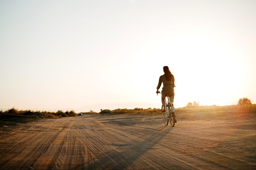 Young woman with a bicycle enjoys cycling to the sea