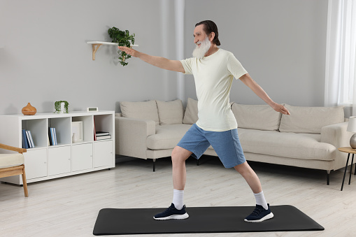 Senior man in sportswear doing exercises at home