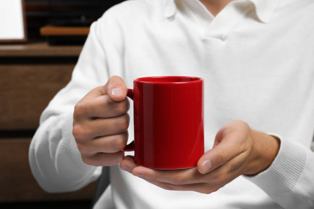 istock Man holding red mug indoors, closeup. Mockup for design 1905737286