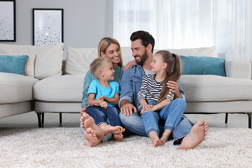 Happy family spending time together on soft carpet at home