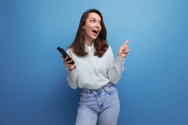 istock young brown-haired woman chatting on the internet using a mobile phone on a studio background with copy space 1905752864