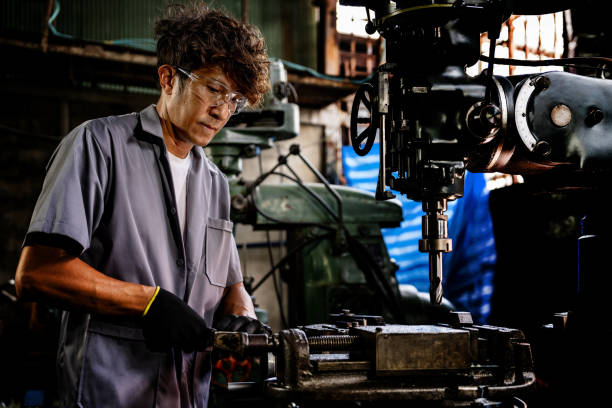 istock Engineer worker in production plant drilling at machine. Professional worker near drilling machine on factory. man inspecting and repairing machine for operation in workshop. 1905754443