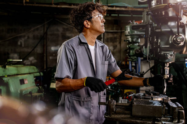 istock Engineer worker in production plant drilling at machine. Professional worker near drilling machine on factory. man inspecting and repairing machine for operation in workshop. 1905755626
