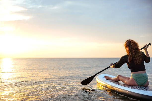 istock Woman swimming on sup boards alone at sunset 1905768066