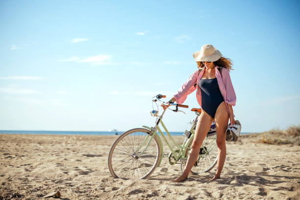 istock Woman with a bicycle on the beach 1905776303