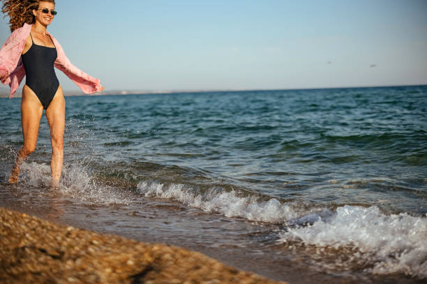 Playful girl running sea waves enjoying cloudy weekend.