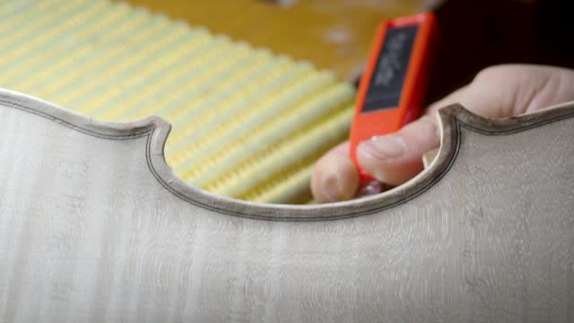 macro close up of artisan luthier maker work on new classic handmade raw violin smooth edge in waist and purfling rasp in workbench of workshop in Cremona Italy 4k video