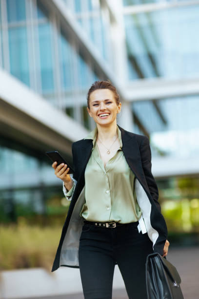 istock happy woman worker in business district using phone and walking 1905832730