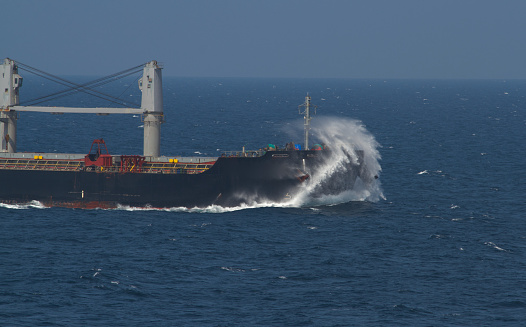 Waves hitting the bow of a merchant ship underway at sea