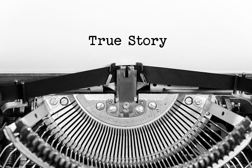 True Story word closeup being typing and centered on a sheet of paper on old vintage typewriter mechanical.