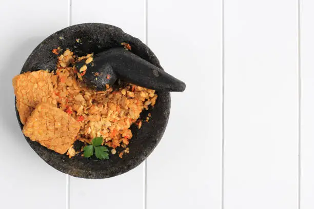 Photo of Sambal Tempeh, Spicy Crushed Tempe on Stone Pestle. Traditional Indonesian Food with Spicy and Savory Taste