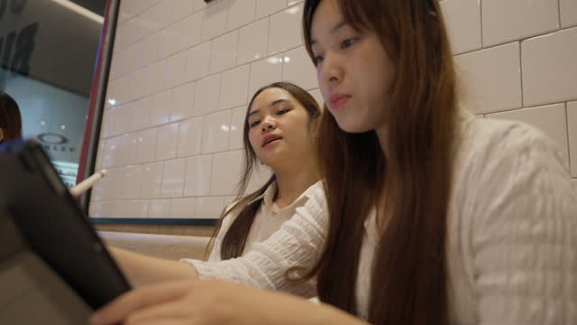 Young businesswomen discuss marketing plans inside a fast food restaurant.