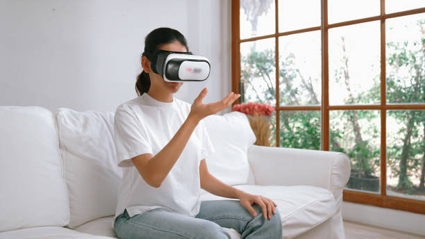 istock Young woman using virtual reality VR goggle at home for vivancy online shopping experience. The virtual reality VR innovation optimized for female digital entertainment lifestyle. 1905922360