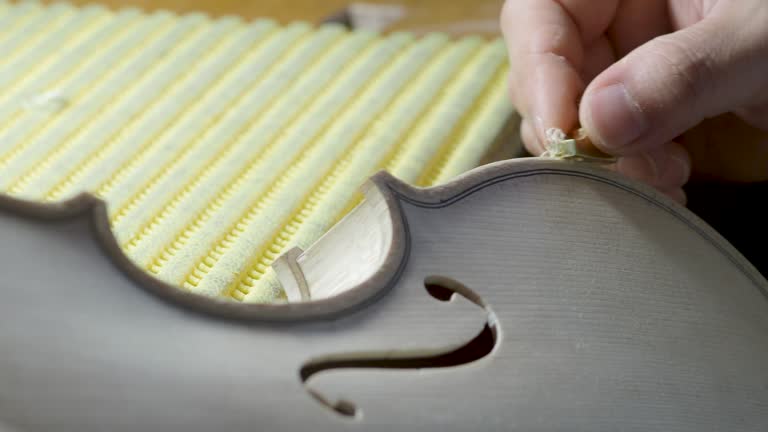 macro close up of artisan luthier maker work on new classic handmade raw violin smooth edge in waist and purfling rasp in workbench of workshop in Cremona Italy 4k video