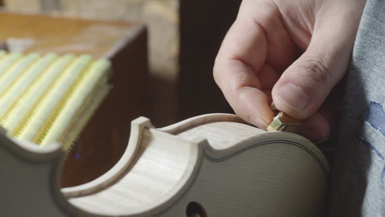 macro close up of artisan luthier maker work on new classic handmade raw violin smooth edge in waist and purfling rasp in workbench of workshop in Cremona Italy 4k video