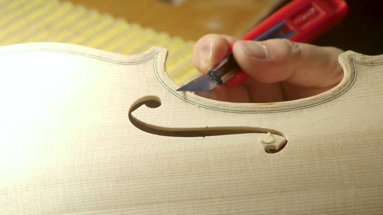 macro close up of artisan luthier maker work on new classic handmade raw violin smooth edge in waist and purfling rasp in workbench of workshop in Cremona Italy 4k video