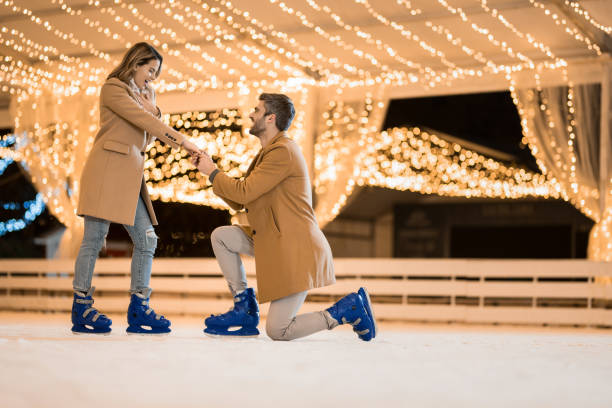 Young man proposing to his girlfriend while ice skating on a holiday.
