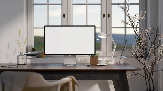 A modern home office with a computer desk near by a window. A white-screen computer with accessories on a hardwood table. 3d render, 3d illustration