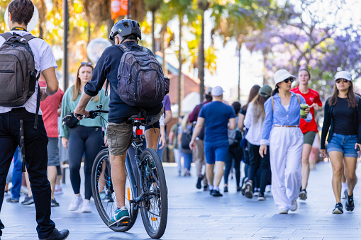 Sydney, Australia - October 29, 2023: Circular Quay, senior male riding bicycle in crowded city street