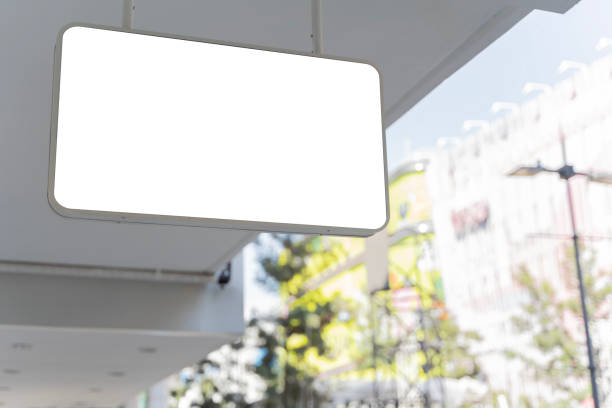 istock A blank white sign hangs from the ceiling of a building. The sign is rectangular and has rounded corners. It is made of a smooth, white material. 1906079047
