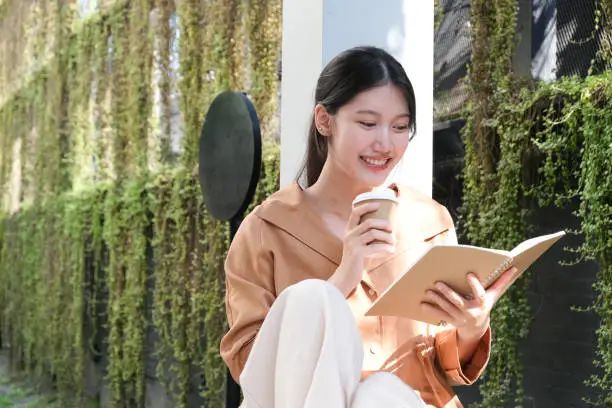 Photo of beautiful girl reading book outdoor and coffeecup lifestyle