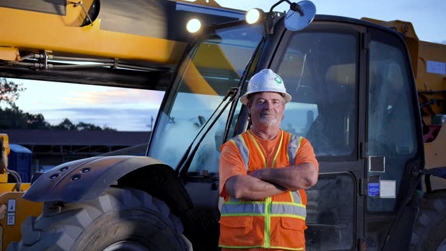 Worker standing in front of construction vehicle