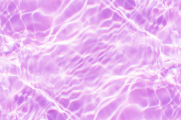 istock Purple water splashes on the surface ripple blur. Defocus blurred transparent pink colored clear calm water surface texture with splash and bubble. Water waves with shining pattern texture background. 1906141443