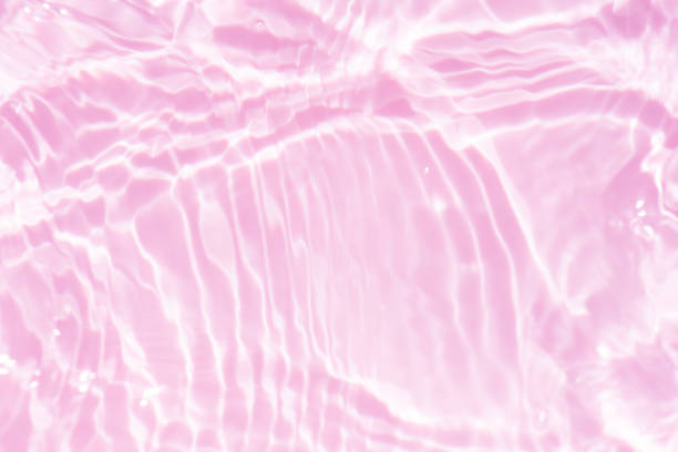istock Purple water splashes on the surface ripple blur. Defocus blurred transparent pink colored clear calm water surface texture with splash and bubble. Water waves with shining pattern texture background. 1906144023
