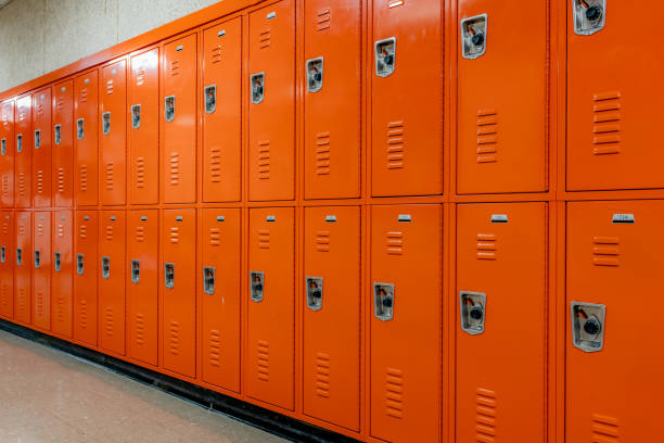 istock Orange metal lockers along a nondescript hallway in a typical US High School.  No identifiable information included and nobody in the hall. 1906152233