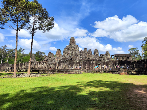 Majestic Bayon, a richly decorated Khmer temple at Angkor in Cambodia. Built in the late 12th or early 13th century as the state temple of the King Jayavarman VII, the Bayon stands at the centre of Jayavarman's capital, Angkor Thom.\nThe Bayon's most distinctive feature is the multitude of serene and smiling stone faces of The Buddha.