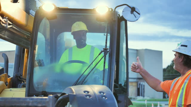 Multiracial workers at job site with construction vehicle